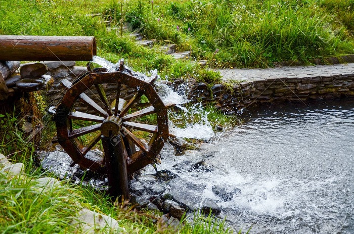 Rueda de molino de agua en funcionamiento con agua que cae en el pueblo